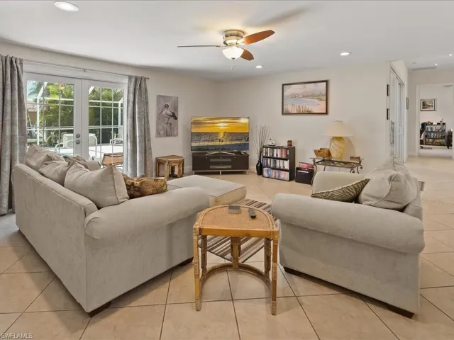 Spacious living area featuring light-toned tile flooring, recessed lighting, and a ceiling fan