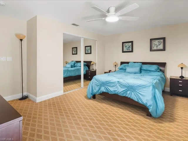 Spacious room featuring patterned carpet flooring, a ceiling fan with integrated lighting, and a large mirrored closet