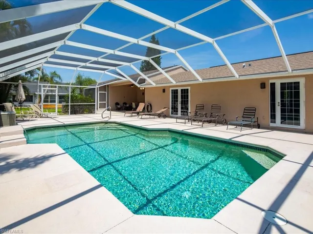 Screened-in swimming pool with a light-colored paved deck