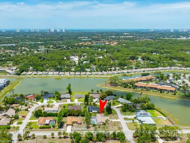 Aerial perspective showcasing a residential property with a private pool, surrounded by mature trees