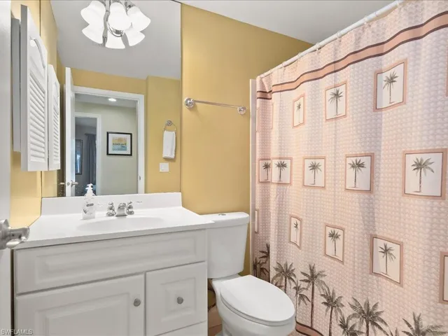 Bathroom featuring a white vanity with integrated sink, chrome faucet, wall-mounted mirror, and a toilet