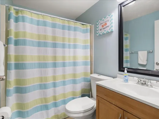 Bathroom featuring a wood-finish vanity with an integrated sink and chrome faucet, a wall-mounted mirror with a black frame, and a toilet