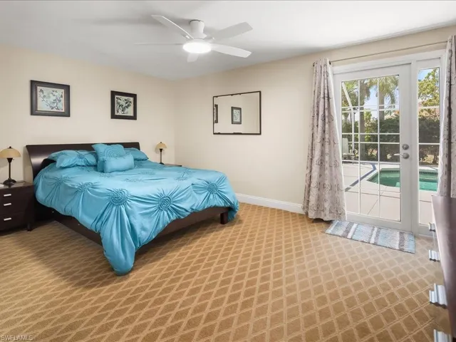 Bedroom featuring patterned carpeting, a ceiling fan with integrated lighting, and a glass-paned door opening to an outdoor pool area