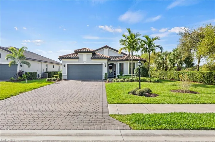 Mediterranean / spanish house featuring a front yard, stucco siding, a garage, decorative driveway, and a tiled roof
