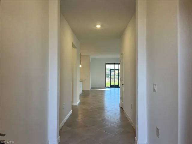 Corridor featuring baseboards and light tile patterned floors
