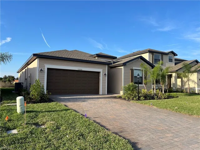 View of front of house featuring decorative driveway, a front lawn, a garage, and a shingled roof