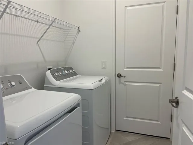 Laundry area with washer and dryer and light tile patterned flooring