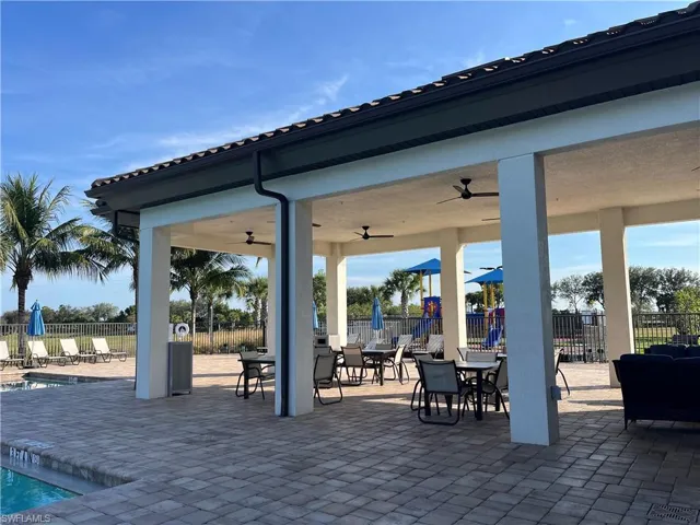 View of patio with ceiling fan, a community pool, and outdoor dining area