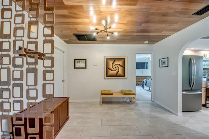 Hall with light tile patterned flooring, wood ceiling, a notable chandelier, and ornamental molding
