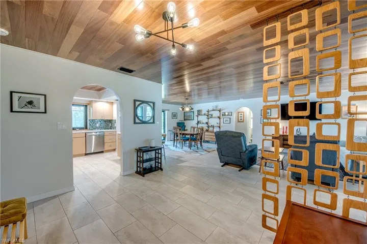 Tiled living room featuring wood ceiling and a notable chandelier