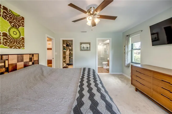 Carpeted bedroom with connected bathroom, a walk in closet, ceiling fan, and a closet