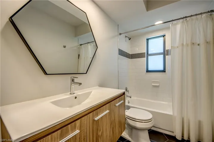 Full bathroom with vanity, toilet, tile patterned floors, and shower / bathtub combination with curtain