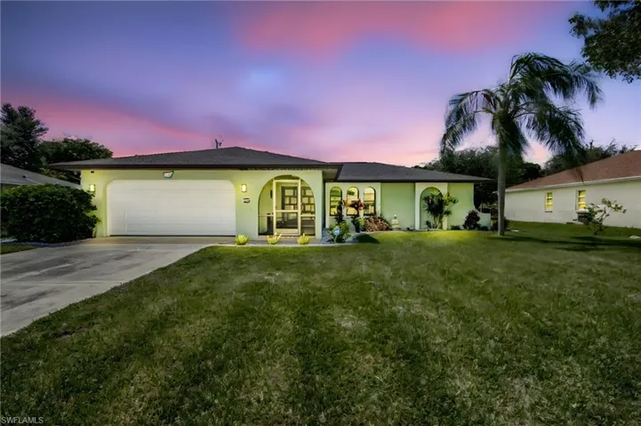 Ranch-style home featuring a garage and a lawn