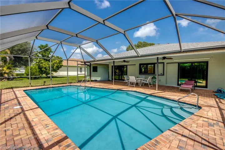 View of swimming pool with glass enclosure, ceiling fan, and a patio