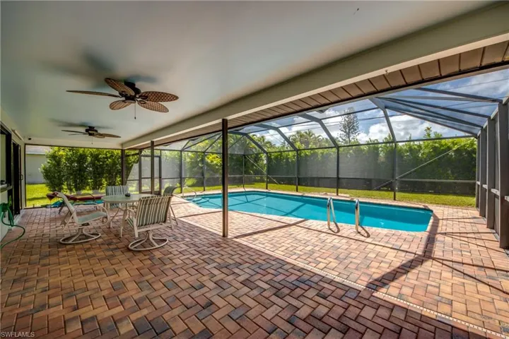 View of swimming pool featuring glass enclosure, ceiling fan, and a patio