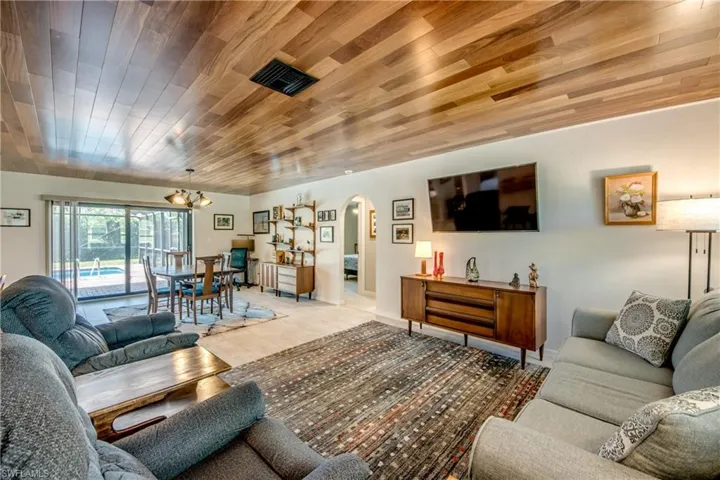 Living room with wooden ceiling, light wood-type flooring, and an inviting chandelier