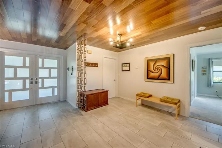 Tiled foyer entrance featuring french doors, an inviting chandelier, and wooden ceiling