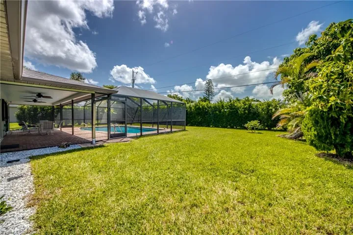 View of yard with a fenced in pool, glass enclosure, a patio area, and ceiling fan