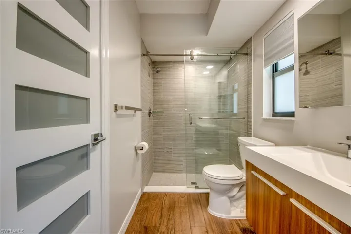 Bathroom featuring vanity, toilet, an enclosed shower, and wood-type flooring