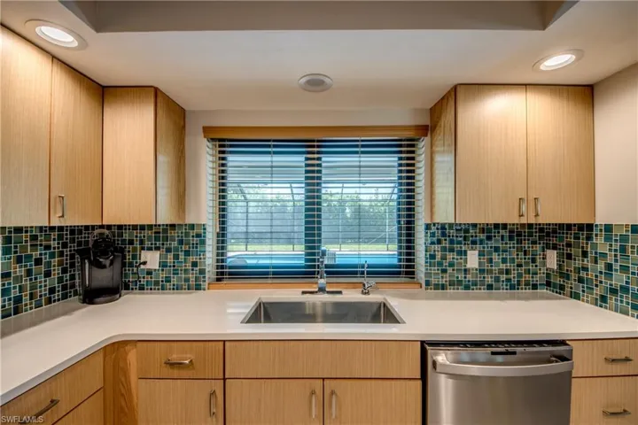 Kitchen featuring stainless steel dishwasher, sink, and light brown cabinets