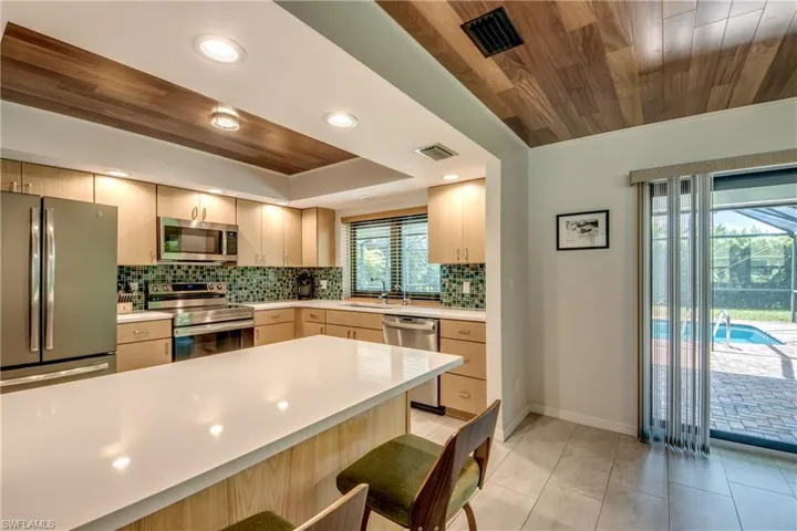 Kitchen featuring a healthy amount of sunlight, stainless steel appliances, and wooden ceiling