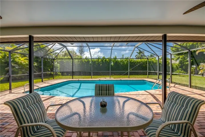 View of pool featuring glass enclosure, a patio area, and ceiling fan