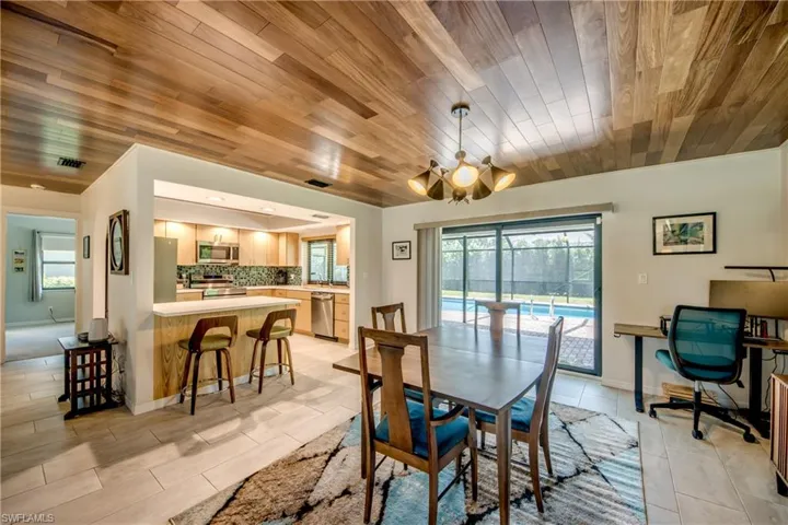 Dining room with wooden ceiling, light tile patterned flooring, and a notable chandelier