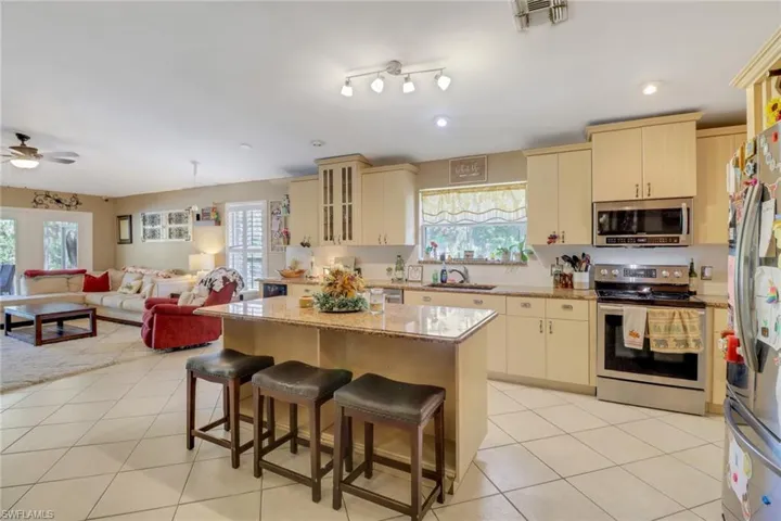 Open Concept Kitchen with spacious island and seating, stainless steel appliances, large pantry, ample cabinet space, granite countertops, wine cooler
