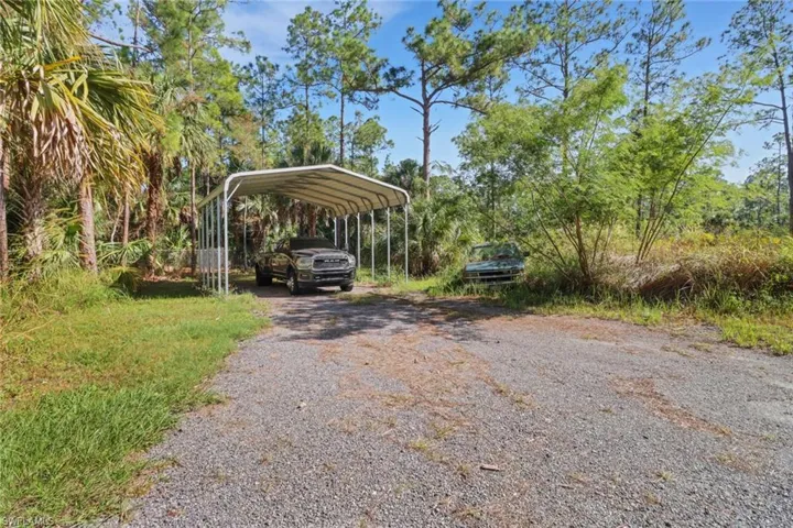 Another view of the back of the lot that has a canopy to park your RV/boat/ or work truck! Also a large cleared space for parking or even to build another home on! This lot is 100% upland