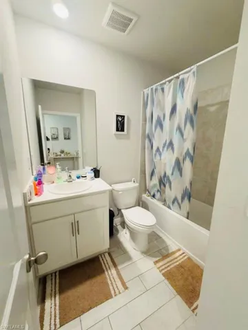 Bathroom featuring vanity, shower / tub combo with curtain, and light tile patterned flooring