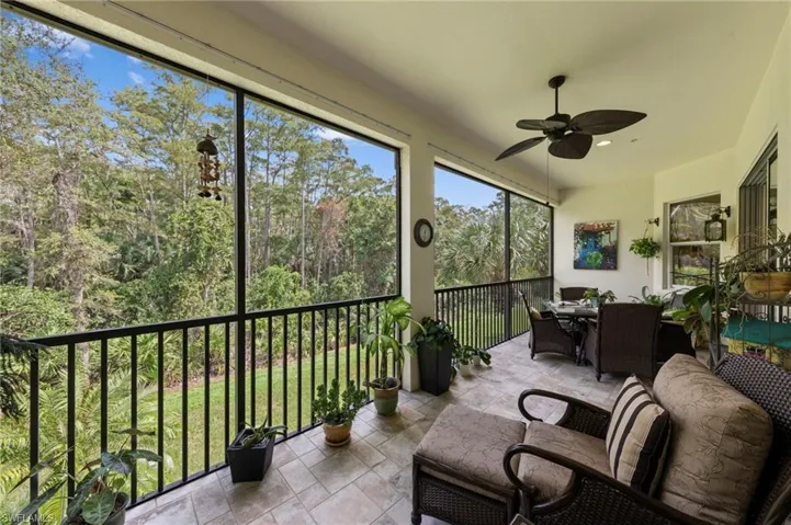 Expansive screened-in lanai with tile flooring, ceiling fan, and black metal railings