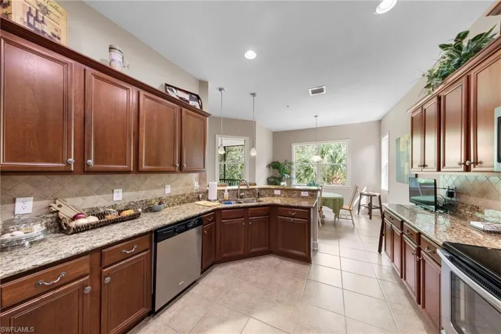 Kitchen featuring wood cabinetry, light-toned countertops, a stainless steel dishwasher, a built-in oven, and recessed lighting