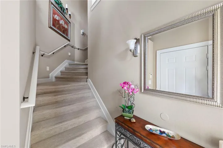 Carpeted staircase with white handrails and sconce lighting