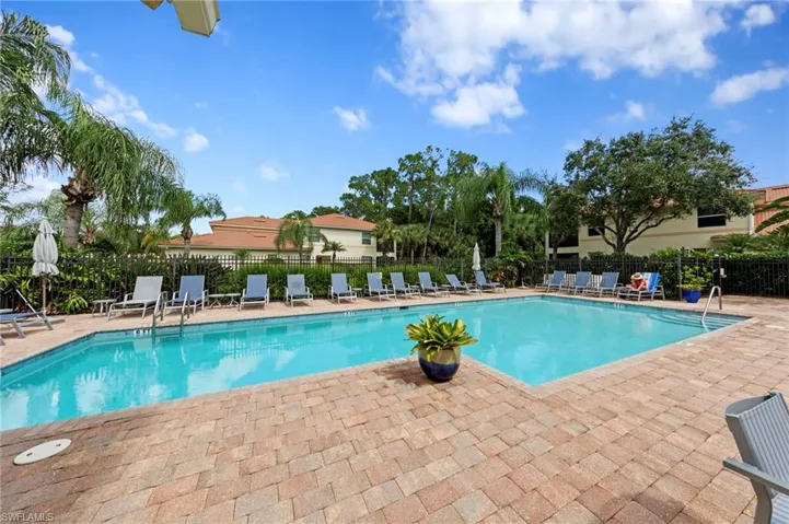 Resort-style pool with a paver deck, surrounded by lush landscaping and a privacy fence