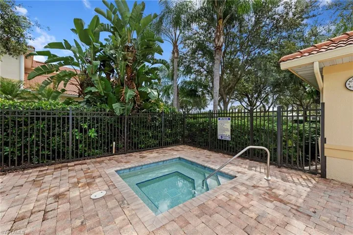 Built-in spa with tiled interior, surrounded by paver decking and framed by a black metal fence