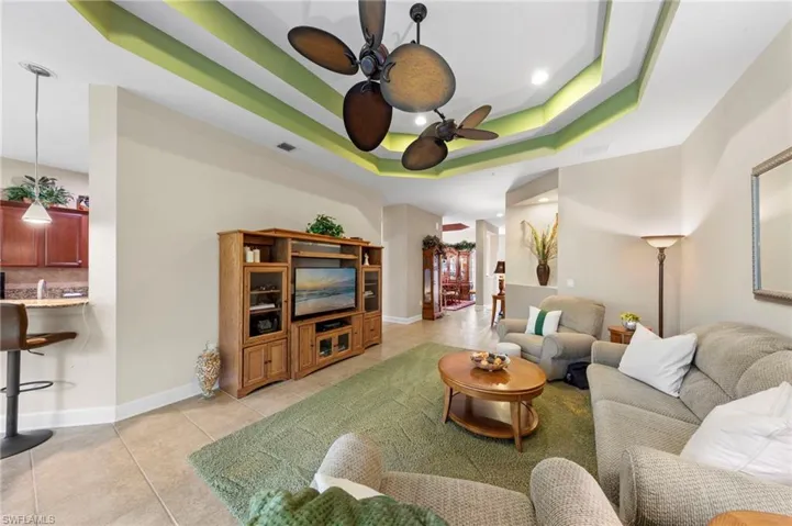 Tray ceiling with accent lighting and a ceiling fan, tile flooring, and recessed lighting