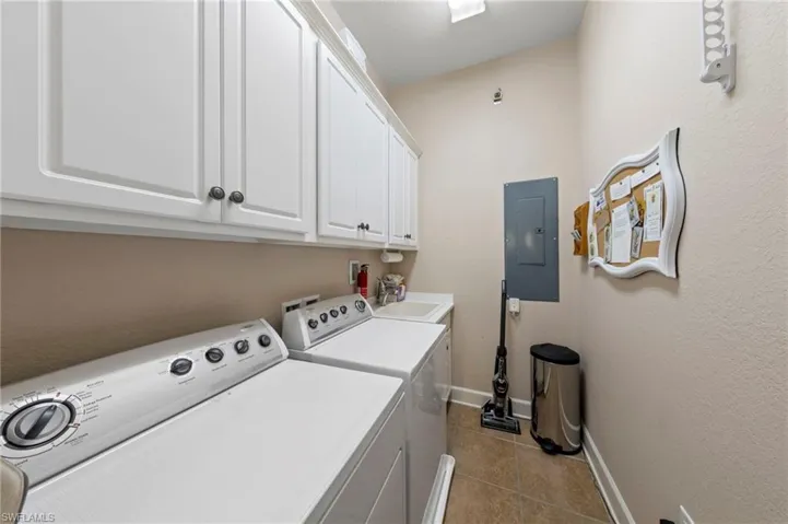 Laundry area featuring upper cabinetry, a utility sink, and tile flooring