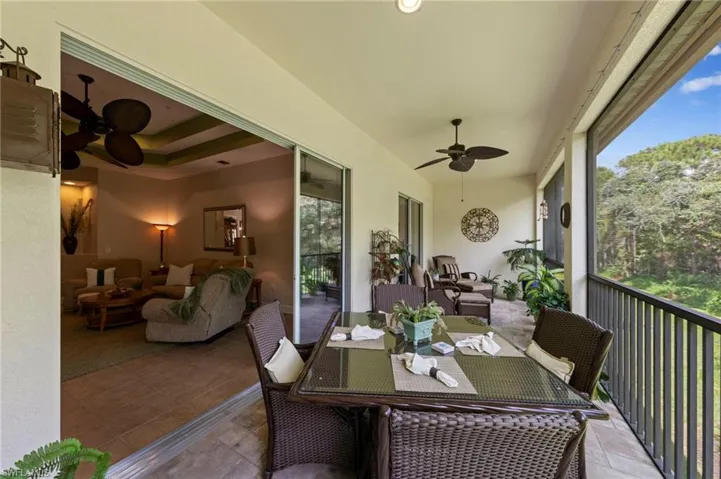 Screened-in balcony with tile flooring, ceiling fans, and a metal railing