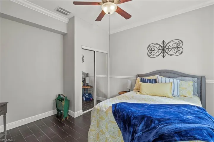 Bedroom with ornamental molding, wood tiled floors, a ceiling fan, and a closet
