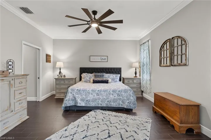 Bedroom featuring ornamental molding, dark wood-style floors, and ceiling fan
