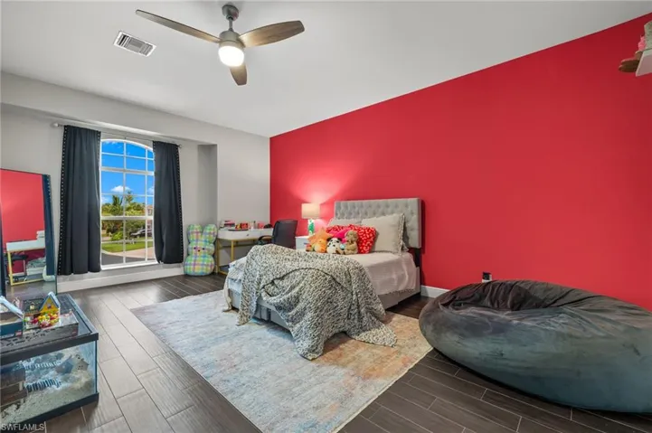Bedroom with wood tiled floors, ceiling fan, and an accent wall