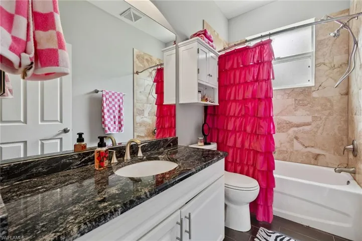 Full bathroom featuring vanity, shower / tub combo with curtain, and wood tiled floors