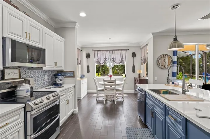 Kitchen with stainless steel appliances, light stone counters, ornamental molding, dark wood-style flooring, and decorative backsplash