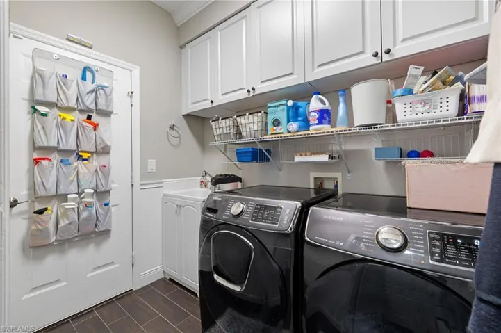 Laundry area featuring separate washer and dryer, wood tiled floors, wainscoting, and cabinet space