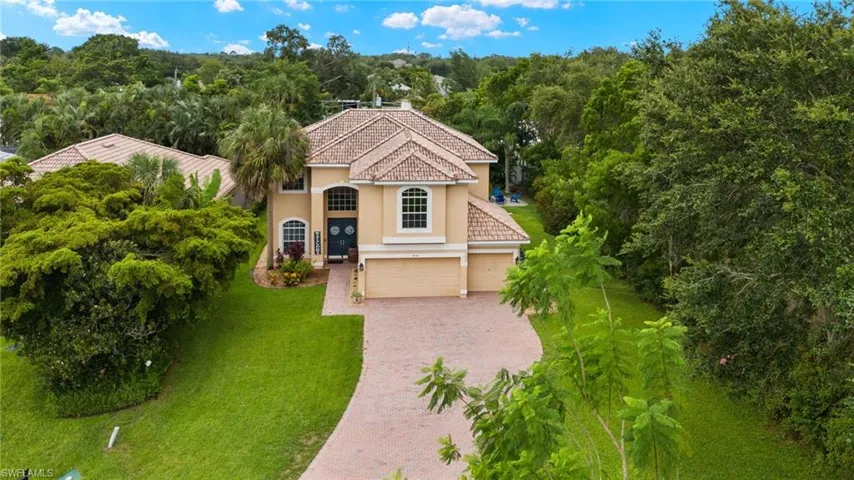 Mediterranean / spanish-style house with stucco siding, a garage, decorative driveway, a front yard, and view of scattered trees