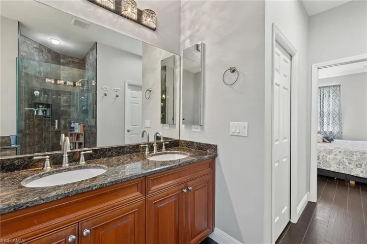 Ensuite bathroom with double vanity, a stall shower, and dark wood-type flooring