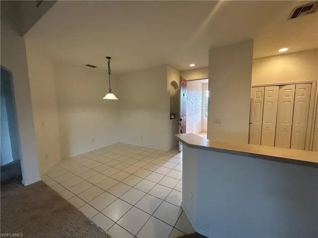 Kitchen with light tile patterned flooring, hanging light fixtures, light carpet, and recessed lighting