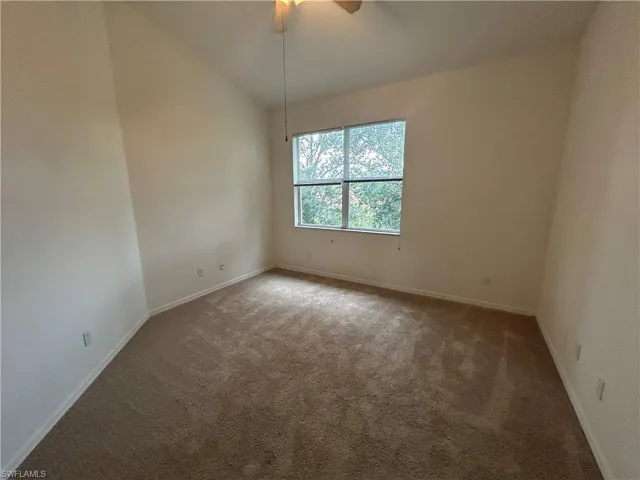 Spare room featuring vaulted ceiling, carpet floors, and a ceiling fan