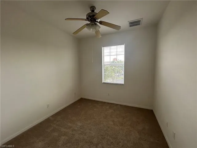 Unfurnished room with dark carpet and ceiling fan