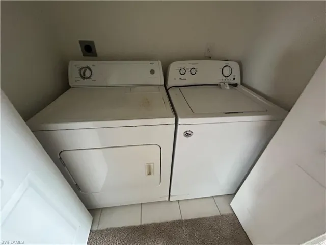 Laundry area featuring light tile patterned flooring and washing machine and clothes dryer